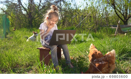 little girl with laptop and chickens in village 69803600