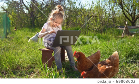 little girl with laptop and chickens in village 69803602