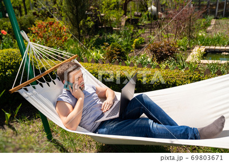 businessman lies in hammock working on computer 69803671