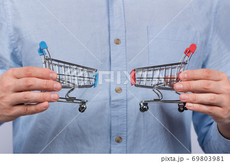 Male hands holding two toy grocery cart. Shopping concept 69803981