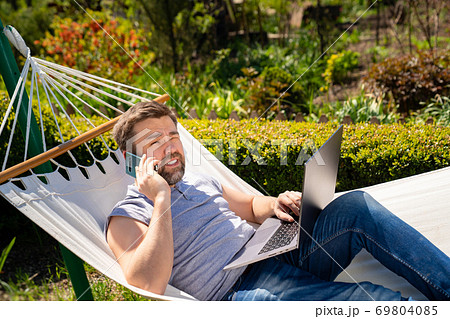 freelancer lies in hammock, working on computer freelancer lies in hammock, working on computer 69804085