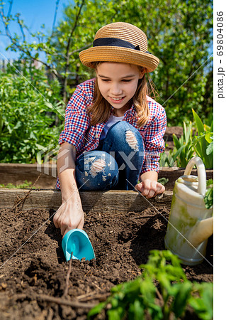 little teen girl in hat planting seedlings 69804086