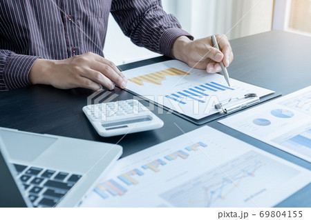The hands of a male businessman are analyzing and calculating the annual income and expenses in a financial graph that shows results To summarize balances overall in office 69804155