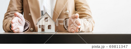 Insurance concept. Agent hand protecting house model that shows to customers to get house insurance. 69811347