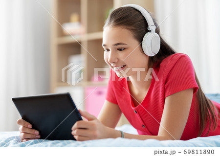 girl in headphones listening to music on tablet pc girl in headphones listening to music on tablet pc 69811890