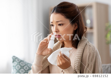 sick asian woman with nasal spray medicine at home 69812152