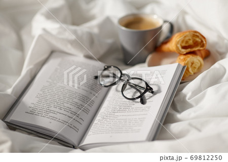 croissants, cup of coffee and book in bed at home 69812250