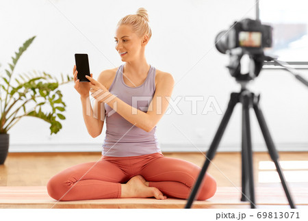 woman with phone streaming for yoga blog at home 69813071