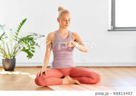 woman with smart watch at home or yoga studio woman with smart watch at home or yoga studio 69813407