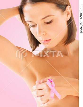young woman checking breast for signs of cancer young woman checking breast for signs of cancer 69813539