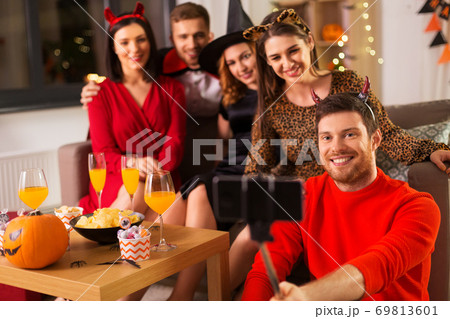 happy friends in halloween costumes taking selfie 69813601