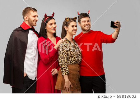 happy friends in halloween costumes taking selfie happy friends in halloween costumes taking selfie 69813602
