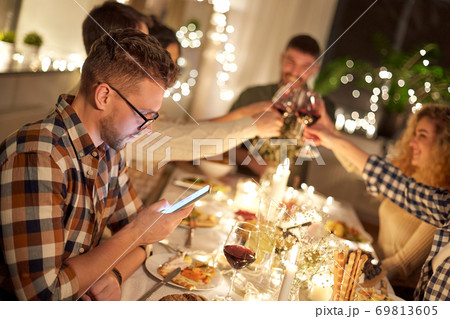man with smartphone at dinner party with friends 69813605