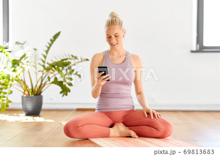 woman with phone and earphones doing yoga at home 69813683