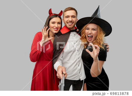 happy friends in halloween costumes taking selfie happy friends in halloween costumes taking selfie 69813878