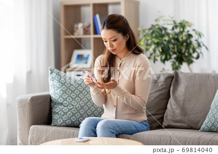 asian woman with glucometer makes blood sugar test 69814040