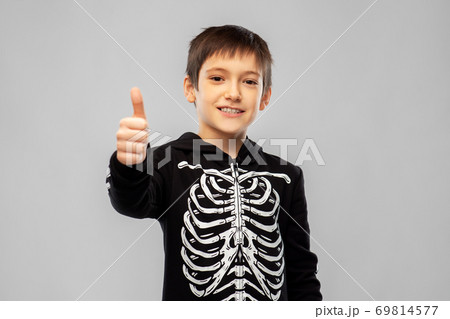 boy in halloween skeleton costume shows thumbs up 69814577