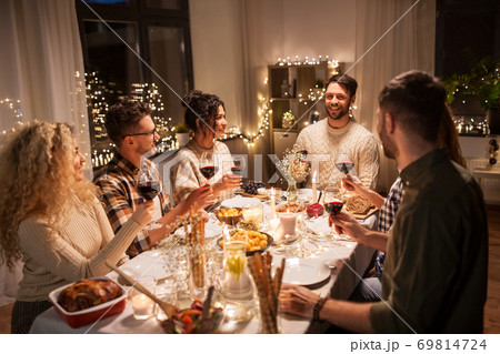 happy friends drinking red wine at christmas party 69814724
