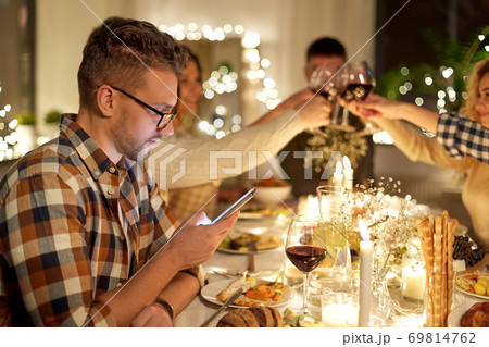 man with smartphone at dinner party with friends 69814762