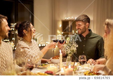 happy friends drinking red wine at christmas party 69814765