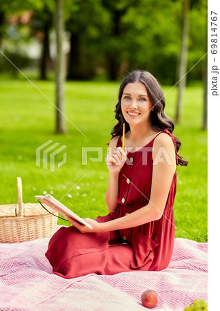 happy woman with diary and picnic basket at park 69814767