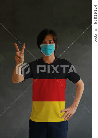 Man wearing hygienic mask and wearing German flag colored shirt Man wearing hygienic mask and wearing German flag colored shirt 69819124