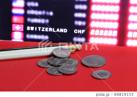 Heap of Swiss coins with white and black pencil on the red floor and digital board Heap of Swiss coins with white and black pencil on the red floor and digital board 69819153