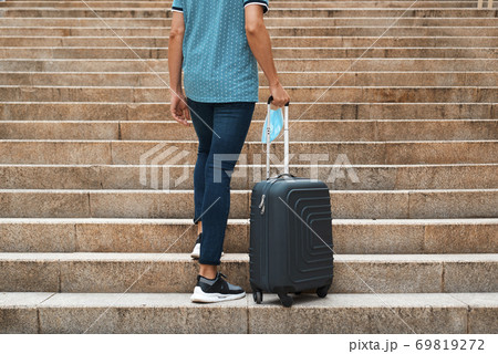 man carrying a suitcase and a face mask 69819272