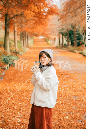 冬の公園でホットドリンクを飲む女性 69820010