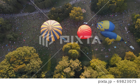 Aerial view of people looking at how hot air balloons prepare for an summer evening flying in park in small european city 69823075