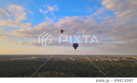 Aerial drone view of colorful hot air balloon flying over green park in small european city at summer sunset Aerial drone view of colorful hot air balloon flying over green park in small european city at summer sunset 69823087