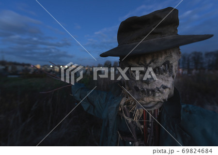 Terrible scarecrow in dark cloak and dirty hat stands alone on a cemetery 69824684