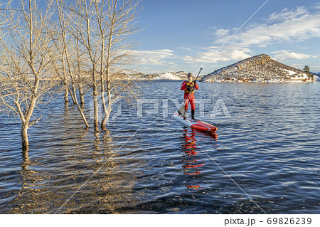 active senior is paddling stand up paddlenboard in winter 69826239