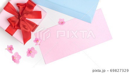 Pink gift box with red bow and blank greeting card for Valentine's day, love letter or wedding invitation. Top view. White background decorated with pink flowers. Pink gift box with red bow and blank greeting card for Valentine's day, love letter or wedding invitation. Top view. White background decorated with pink flowers. 69827329