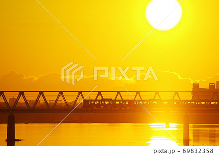 朝焼けと多摩川橋梁を通過する京王線の写真素材