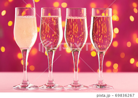 Four champagne glasses against pink background with blurred garland Four champagne glasses against pink background with blurred garland 69836267