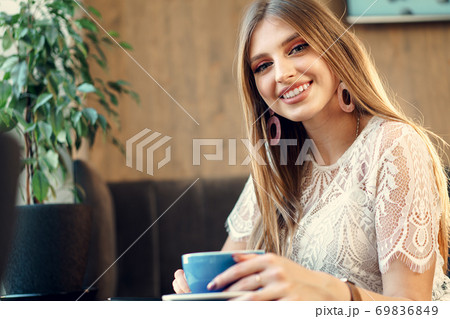Nice young woman enjoying cup of coffee in a coffee shop Nice young woman enjoying cup of coffee in a coffee shop 69836849