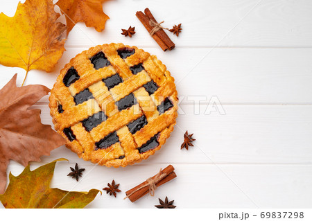Autumn thankgiving pie on white wooden board decorated with dry leaves and cinnamon sticks 69837298