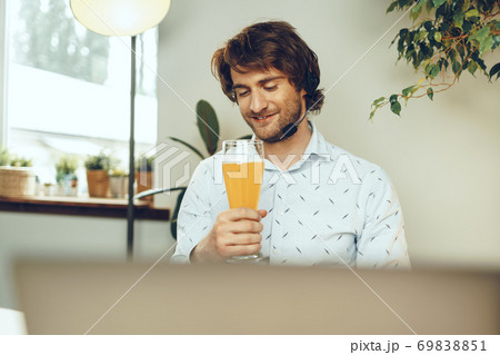 Bearded man using his laptop while drinking glass of beer 69838851