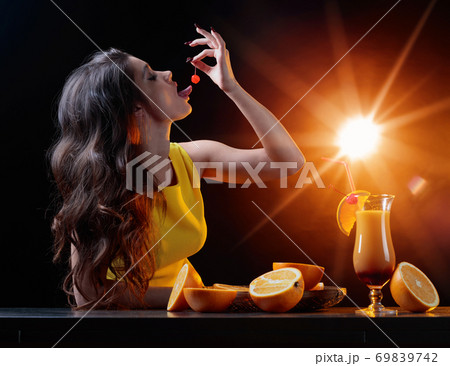 Young beautiful girl in a yellow dress with cocktail Tequila Sunrise. Young beautiful girl in a yellow dress with cocktail Tequila Sunrise. 69839742