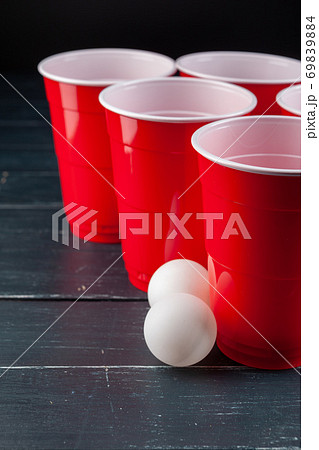 Wooden table with red cups and ball for beer pong 69839884