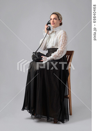 Portrait of a woman in retro clothes with a old black phone. 69840468