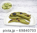 白い木製テーブル上の白いお皿の上の焼きソラマメと茹でソラマメ 69840703