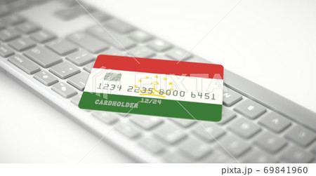 Plastic bank card depicting flag of Tajikistan on computer keyboard. Fictional numbers 69841960