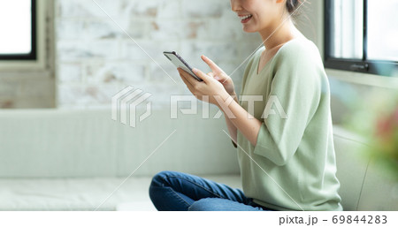 笑顔でスマートフォンを見る女性 笑顔でスマートフォンを見る女性 69844283