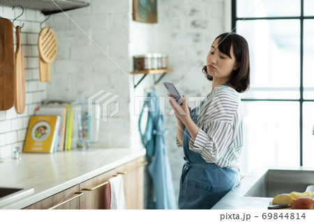 キッチンでスマホを眺める主婦 69844814
