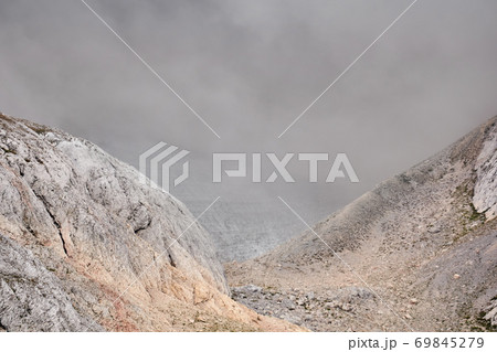 gloomy alpine canyon partially obscured by a cloud 69845279