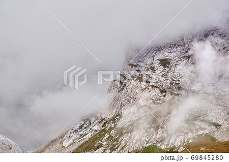 steep rocky slope partially obscured by a cloud 69845280