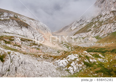 rocky alpine gorge partially obscured by a cloud 69845281
