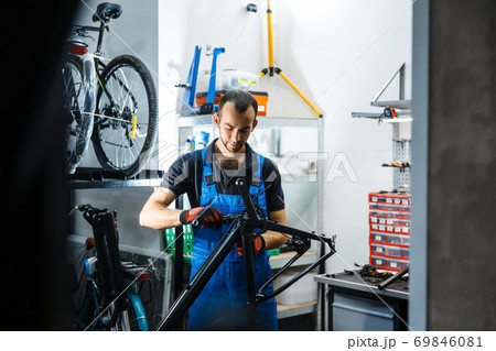 Bicycle repair in workshop, man fixing crank 69846081
